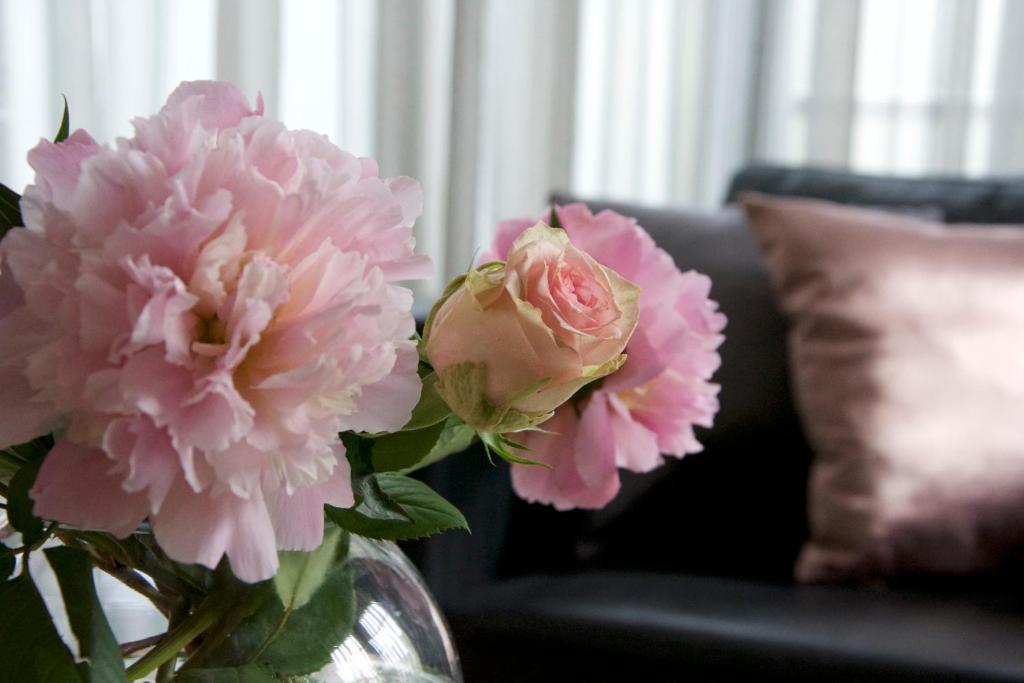 un jarrón lleno de flores rosas delante de un sofá en Faupel Ferienwohnung en Mülverstedt