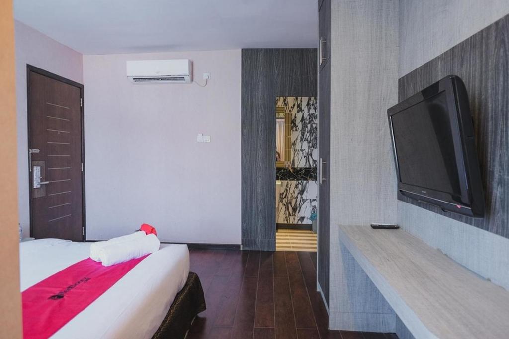 a hotel room with a bed and a flat screen tv at RedDoorz Plus near Pantai Coastarina 2 Batam in Batam Center