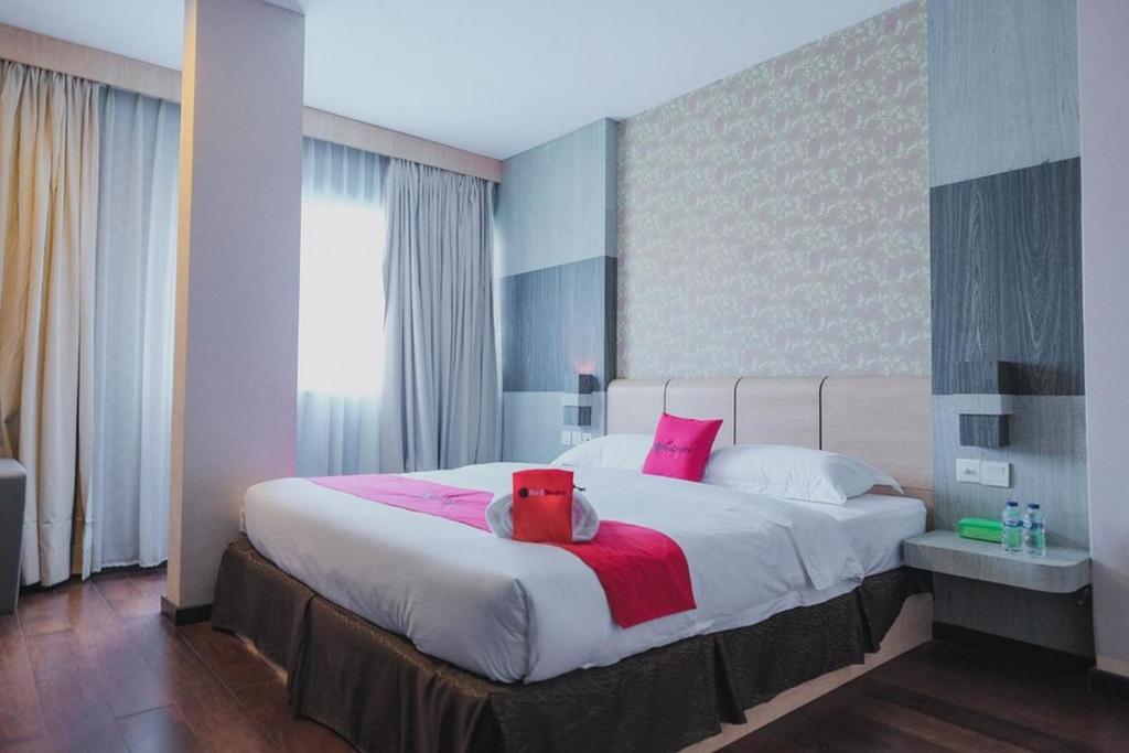 1 dormitorio con 1 cama grande con almohadas rosas en RedDoorz Plus near Pantai Coastarina 2, en Batam Centre
