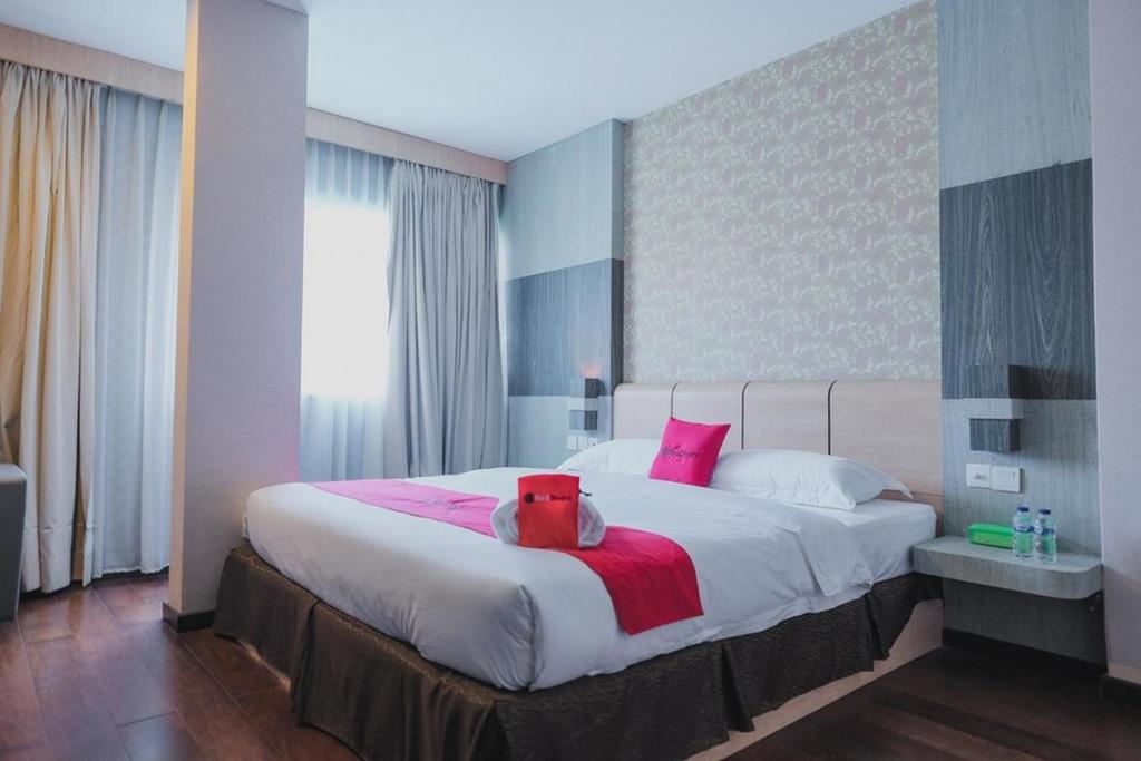 a bedroom with a large bed with pink pillows at RedDoorz Plus near Pantai Coastarina 2 Batam in Batam Center