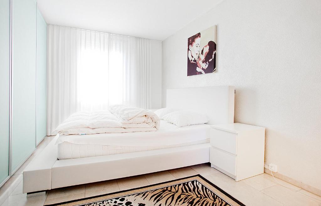 a white bedroom with a bed and a window at Junior Suite Apartment by Livingdowntown in Zurich