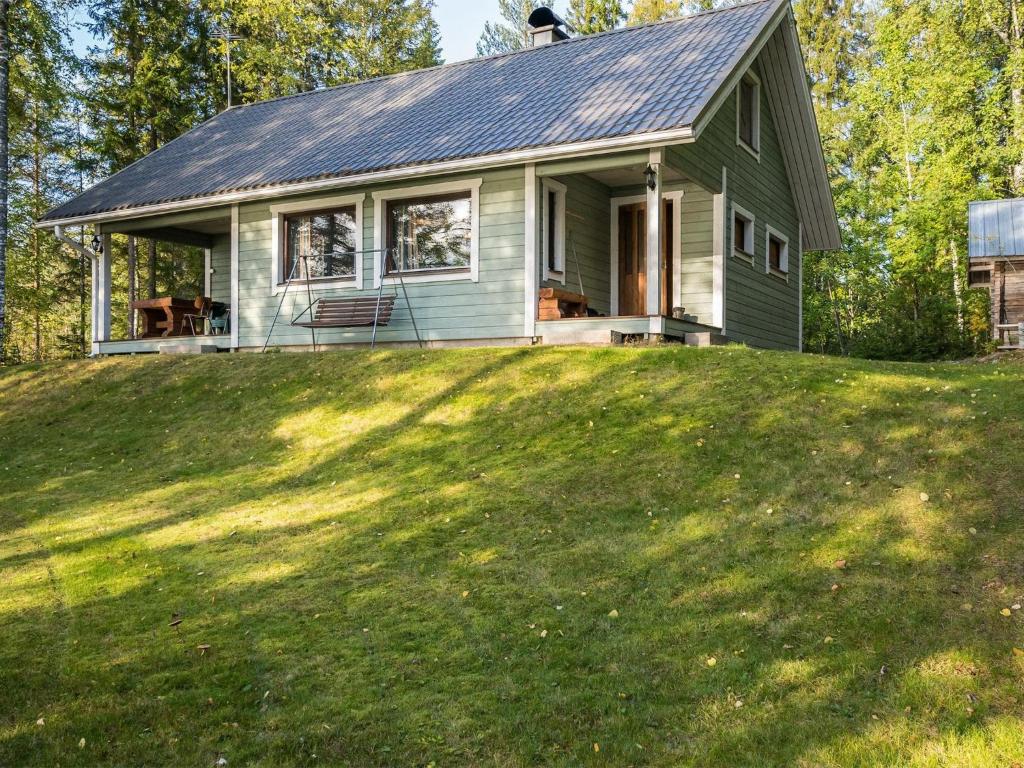uma casa verde no topo de uma colina relvada em Holiday Home Heikinniemi by Interhome em Vanaja