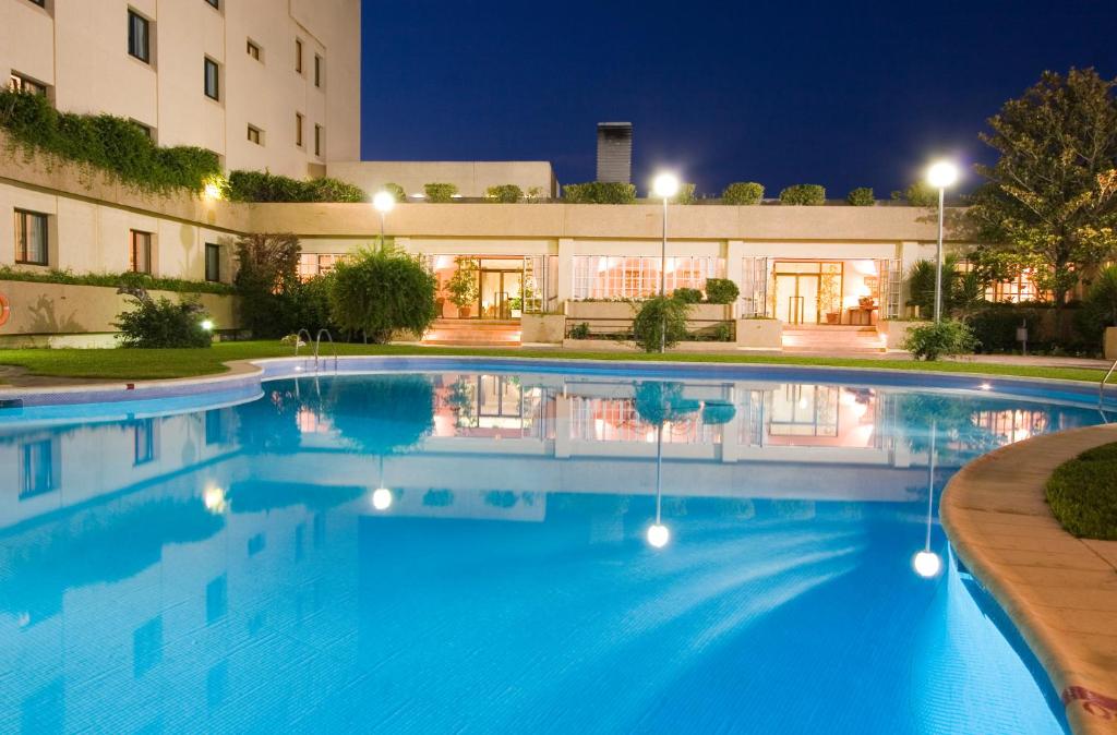 a swimming pool in front of a building at night at Hotel Vegas Altas in Don Benito