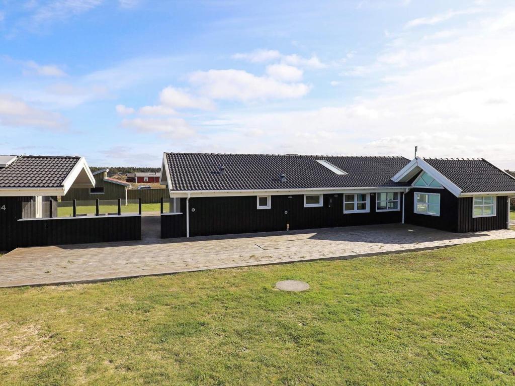 a house with a black roof and a yard at Four-Bedroom Holiday home in Løkken 28 in Lønstrup