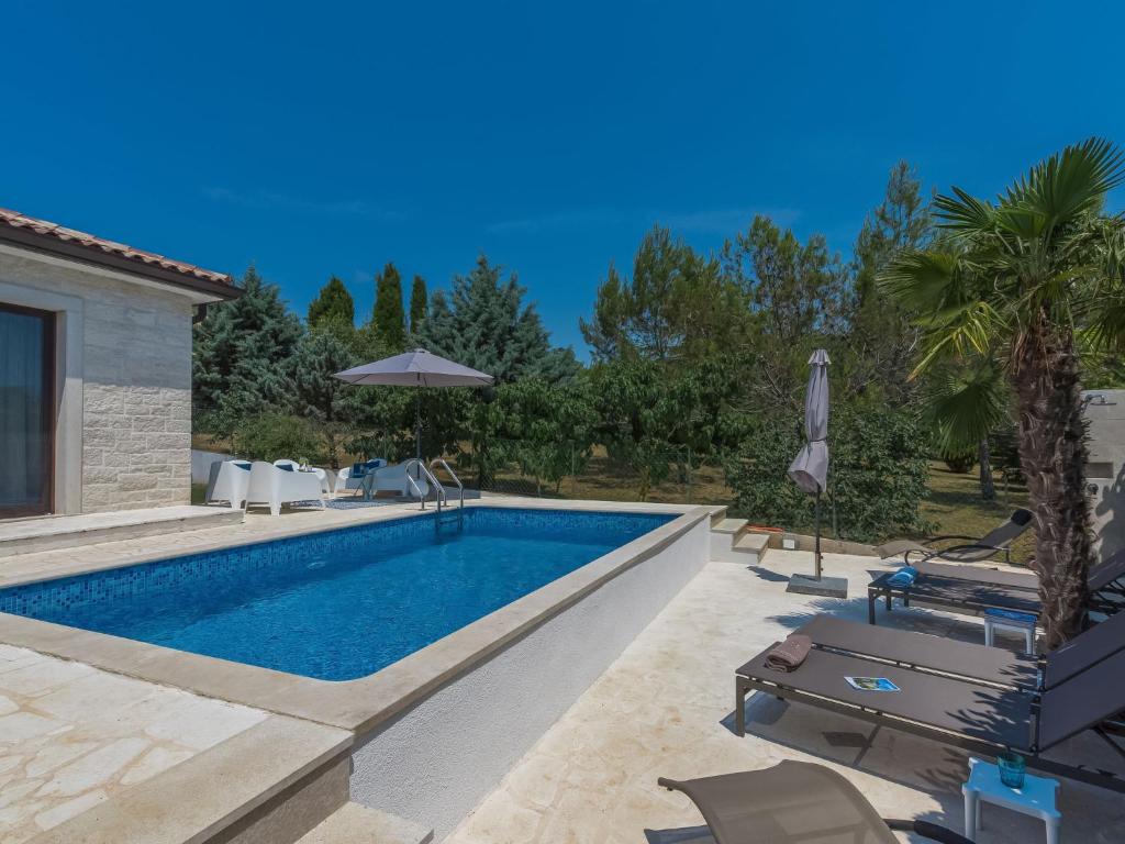 basen z krzesłami i parasolem na dziedzińcu w obiekcie Holiday Home Villa Joy by Interhome w mieście Novigrad