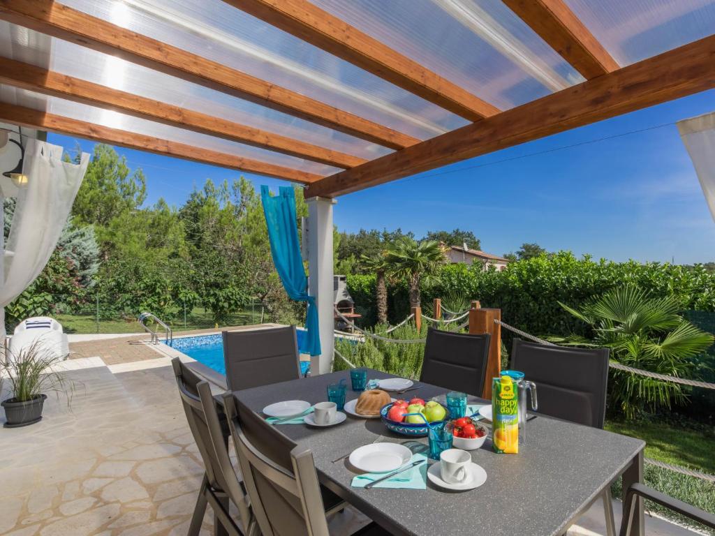 taras ze stołem i krzesłami oraz basenem w obiekcie Holiday Home Villa Joy by Interhome w mieście Novigrad