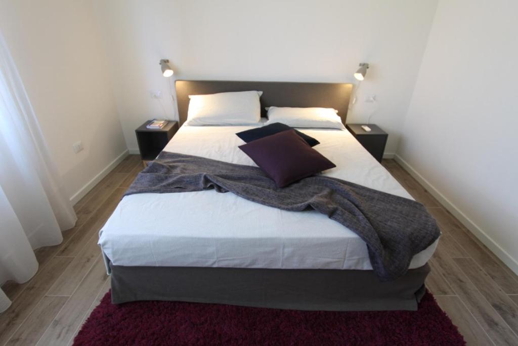 ein Schlafzimmer mit einem großen Bett mit weißer Bettwäsche und Kissen in der Unterkunft LA CASABELLA in Terralba