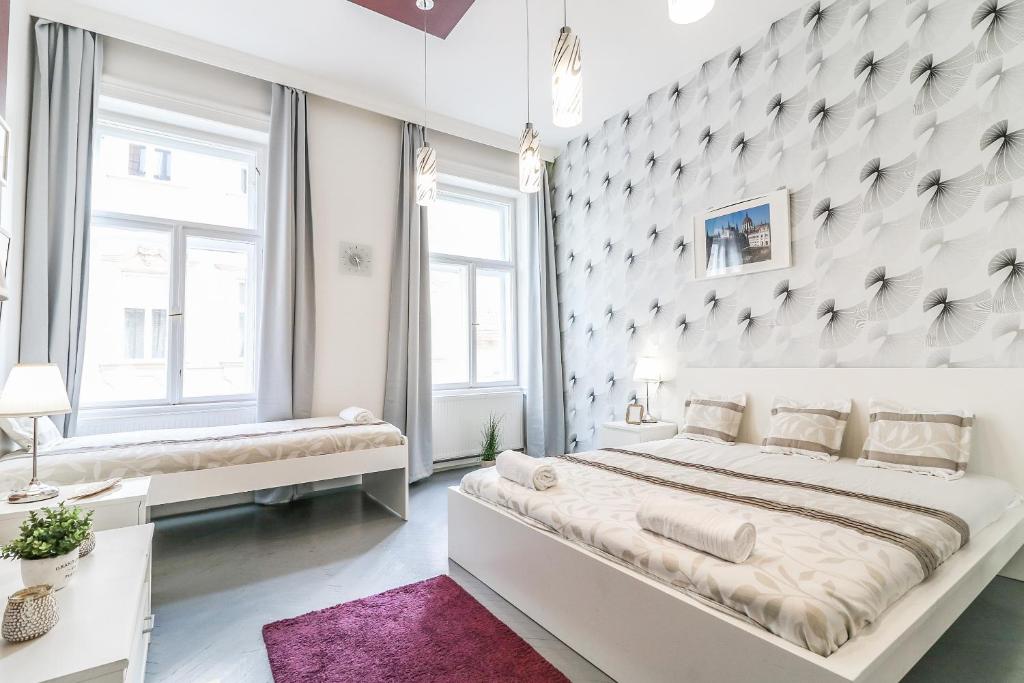 a white bedroom with a large bed and two windows at Real Apartments Hegedű in Budapest