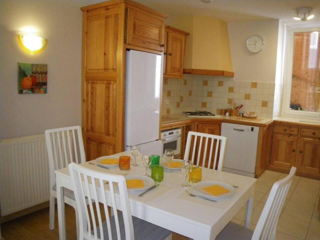 eine Küche mit einem weißen Tisch mit Stühlen und einem weißen Kühlschrank in der Unterkunft La Galerie Privée in Pontcharra
