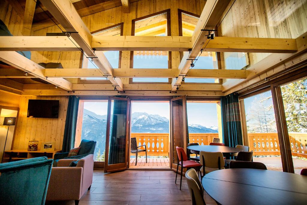 a room with tables and chairs and large windows at Chalet l’Aiglon in La Rosière