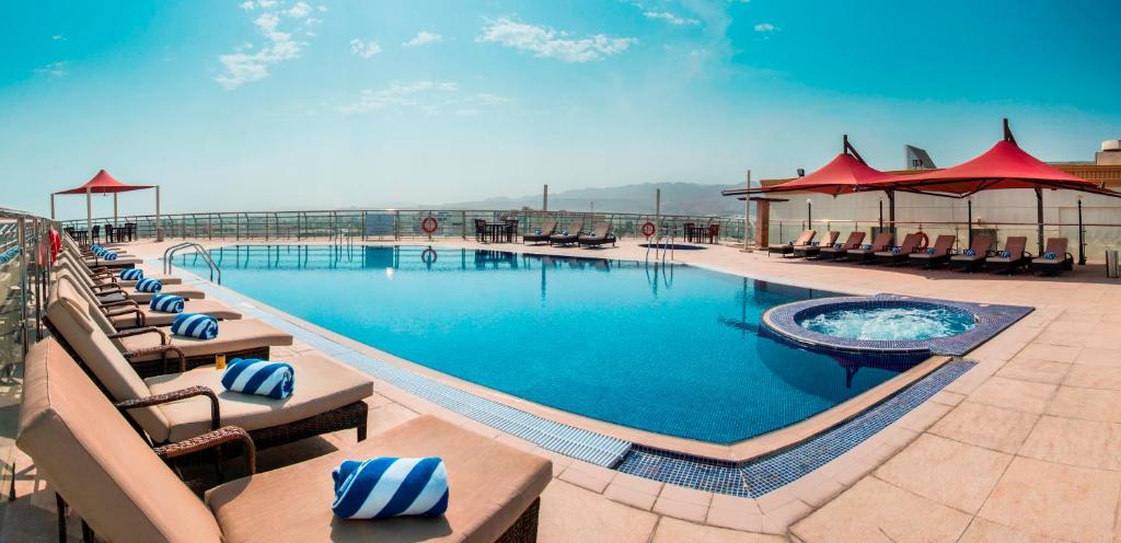 a pool with chairs and tables in it at City Seasons Hotel & Suites Muscat in Muscat