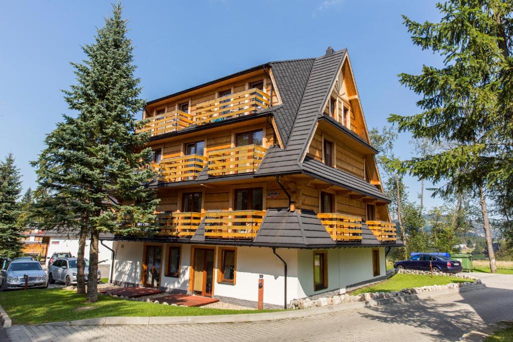 a large wooden building with a metal roof at udanypobyt Apartamenty Przy Dolinach C i D in Kościelisko