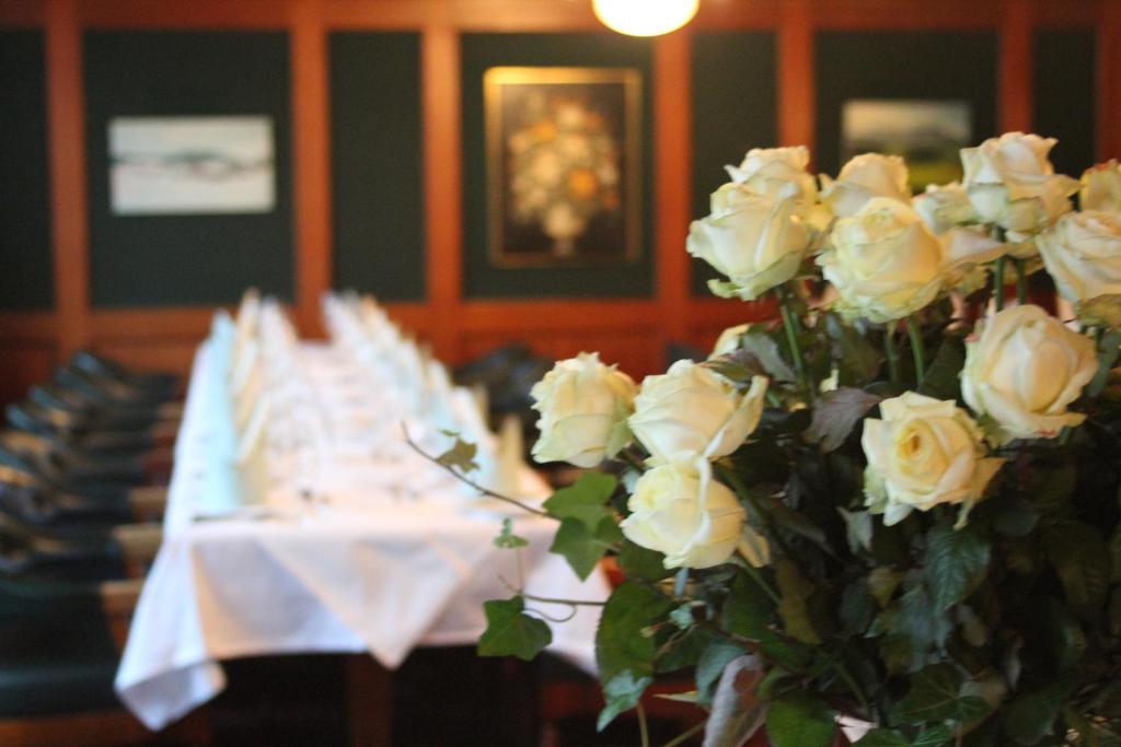 una fila de mesas con rosas blancas. en Hotel Bramen, en Kloten