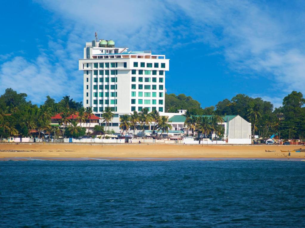 un edificio blanco en la playa con una playa en The Quilon Beach Hotel and Convention Center, en Kollam