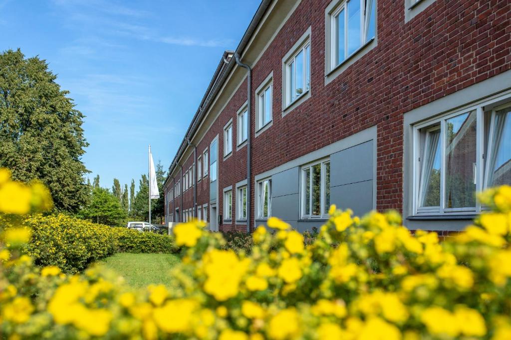 un bâtiment en briques avec des fleurs jaunes devant lui dans l'établissement Hotel Rügenblick, à Stralsund