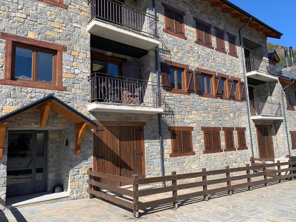 un edificio de piedra con puertas de madera y una valla en El Estacho de Panticosa en Panticosa