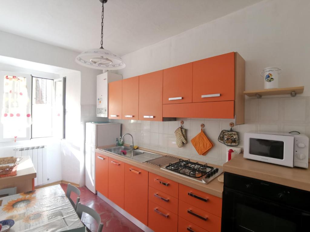 a kitchen with orange cabinets and a microwave at Appartamento Liliana in Pontremoli