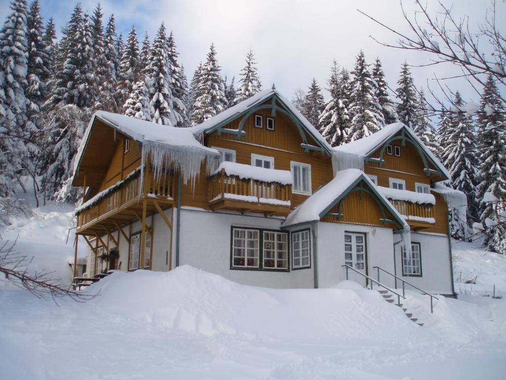 ein schneebedecktes Haus vor Bäumen in der Unterkunft Pension Rychta in Hojsova Stráž