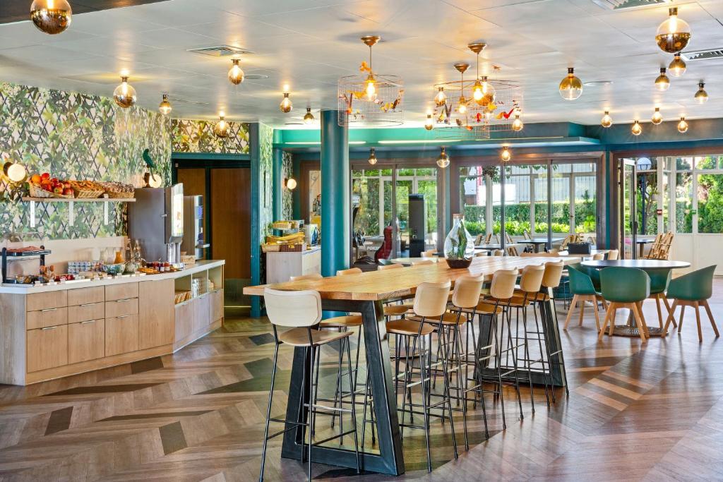 a restaurant with a long table and chairs at Best Western Hôtel Grand Parc Marne La Vallée in Chanteloup-en-Brie