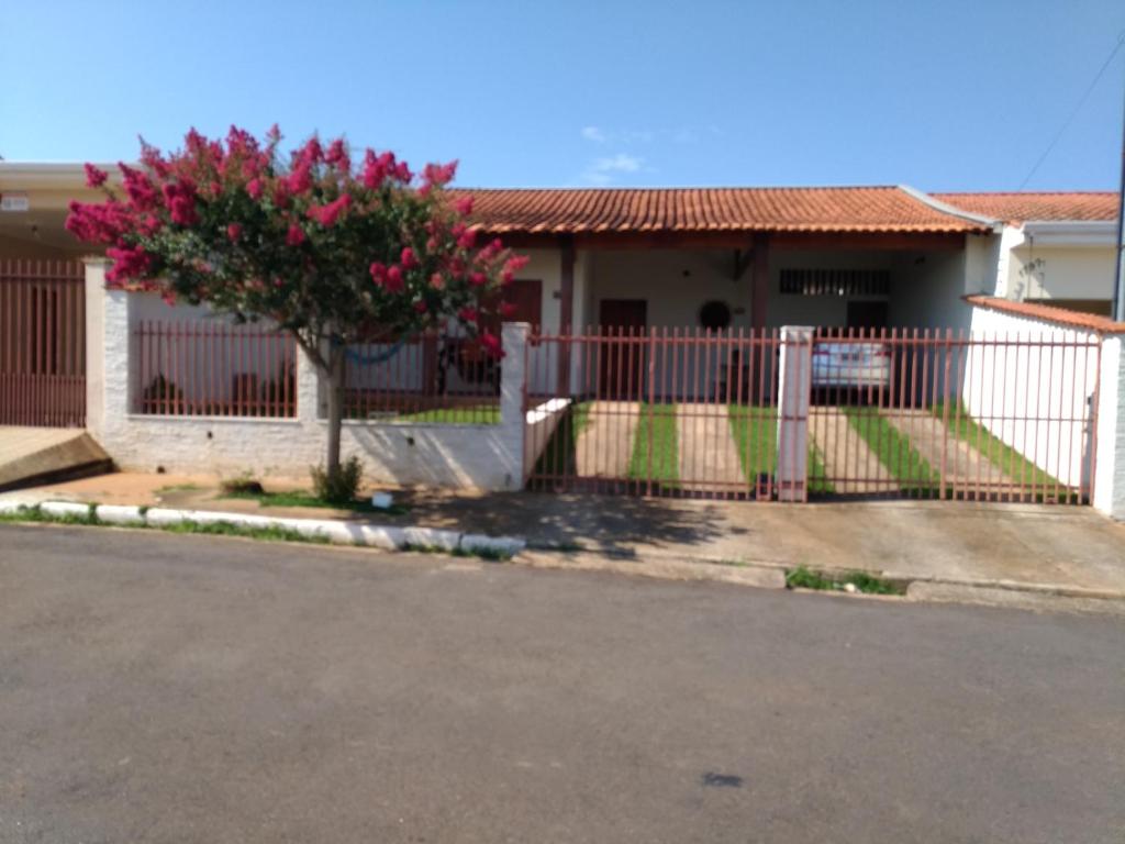 a fence in front of a house with a tree at Quarto para uma pessoa com banheiro exclusivo in Alfenas