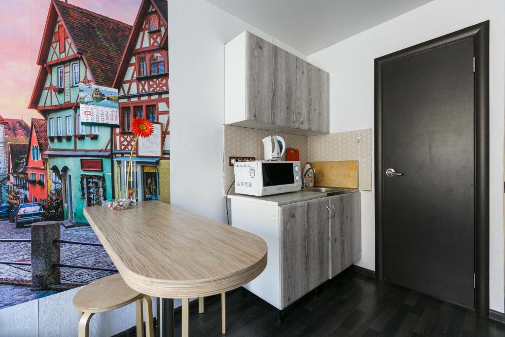 a kitchen with a wooden table and a microwave at Welcome Apartment, уютные апартаменты-студия, 20м до метро in Novosibirsk