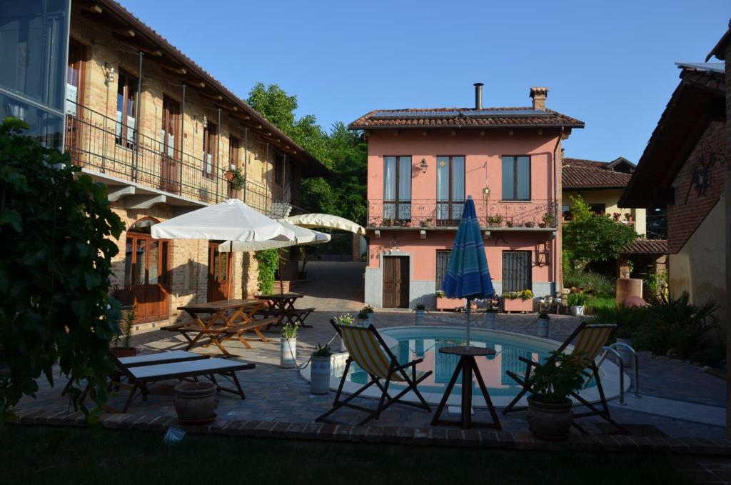 un patio con sillas, una sombrilla y una piscina en La Corte Di Gerardo, en Tonco