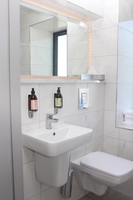 a white bathroom with a sink and a toilet at Baginbun Lodge in Fethard on Sea