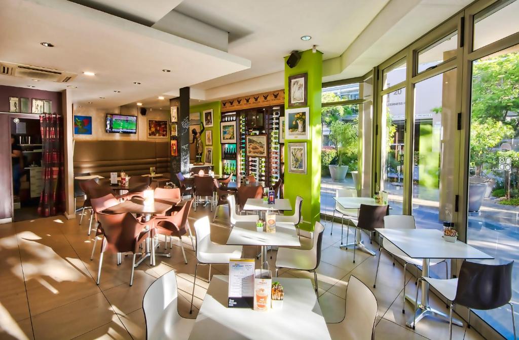 ein Restaurant mit Tischen und Stühlen und Fenstern in der Unterkunft SunnyA206 The Quadrant in Kapstadt