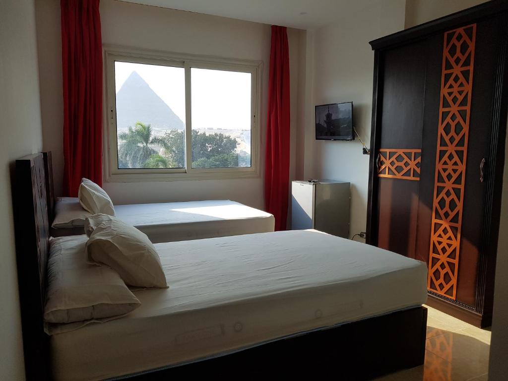um quarto com 2 camas e uma janela com uma pirâmide em Sahara Pyramids Inn em Cairo