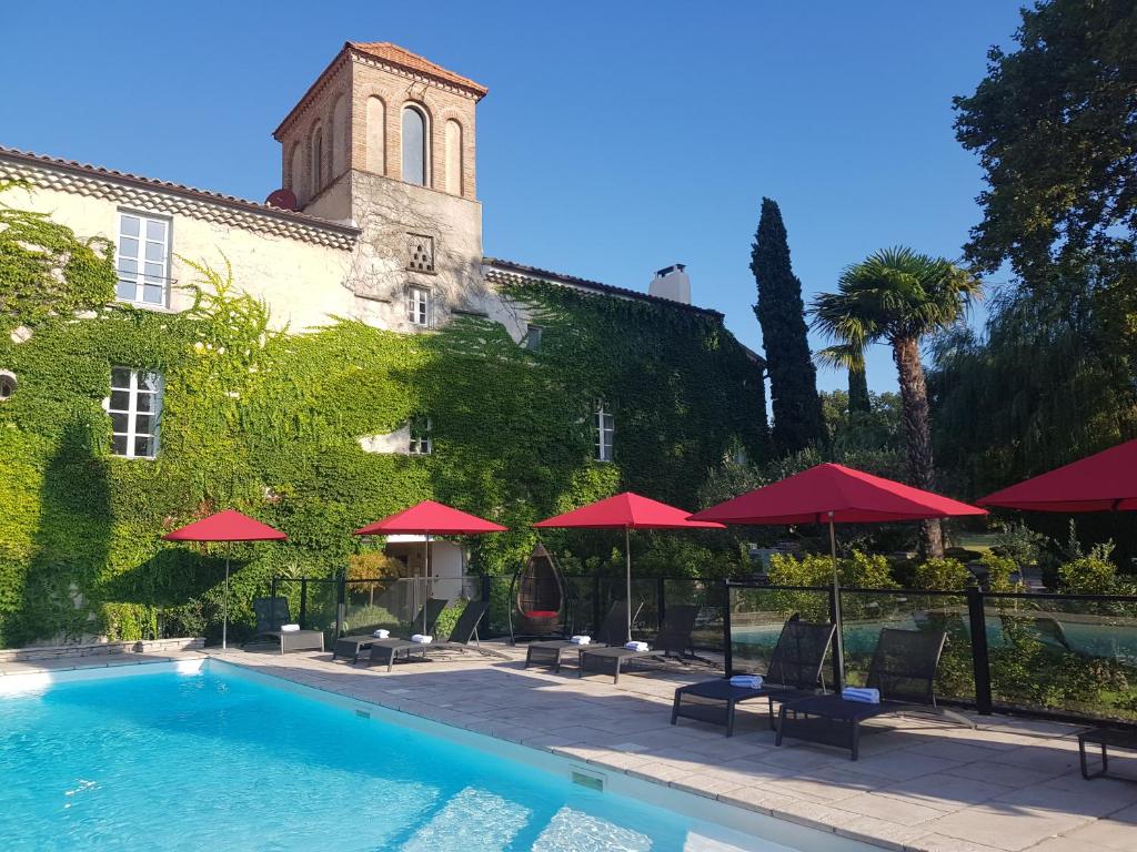 a hotel with a swimming pool and red umbrellas at Le Domaine Du Colombier in Malataverne