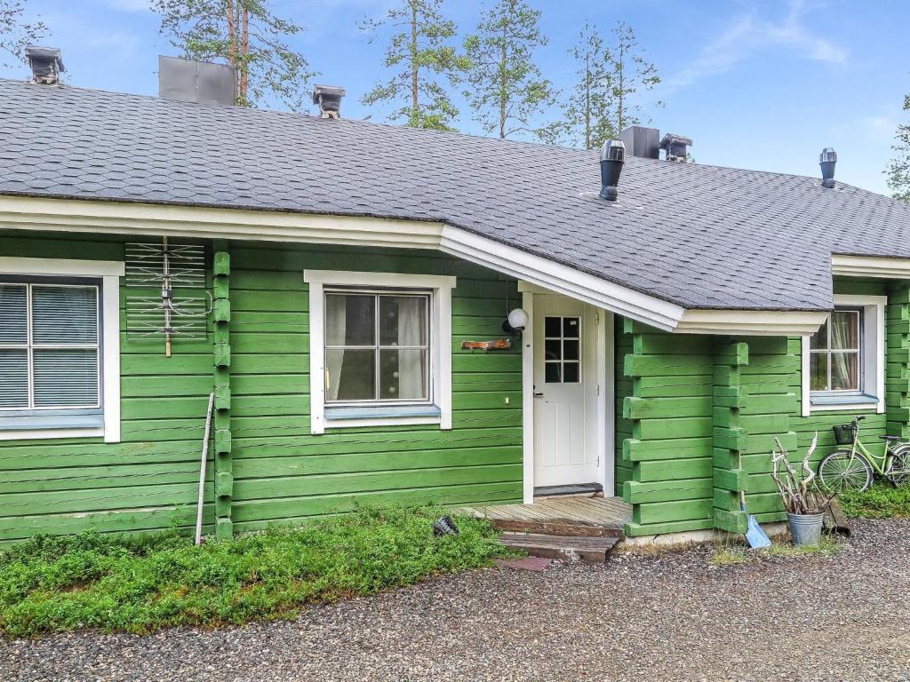 a green house with a white door at Holiday Home Ylläsmukka a 3 by Interhome in Äkäslompolo