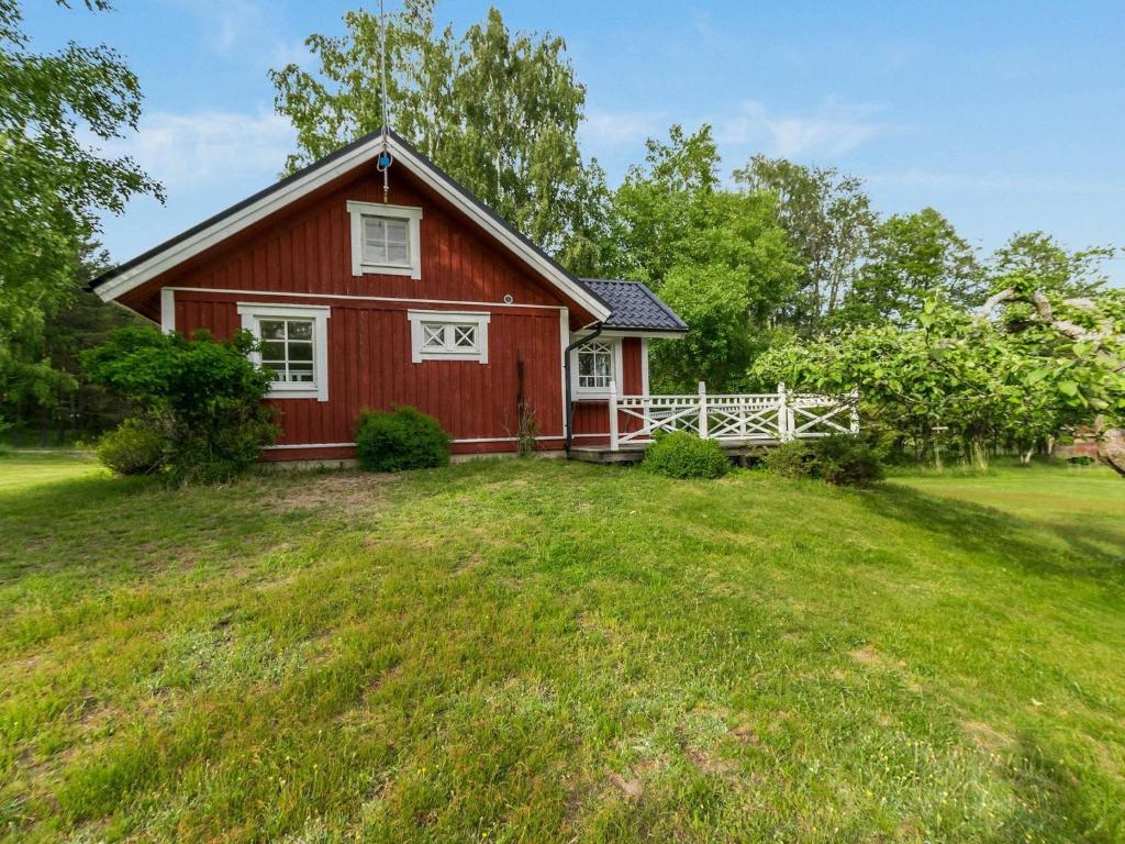 een rode schuur met een wit hek in een tuin bij Holiday Home Lilla nennebo by Interhome in Förby