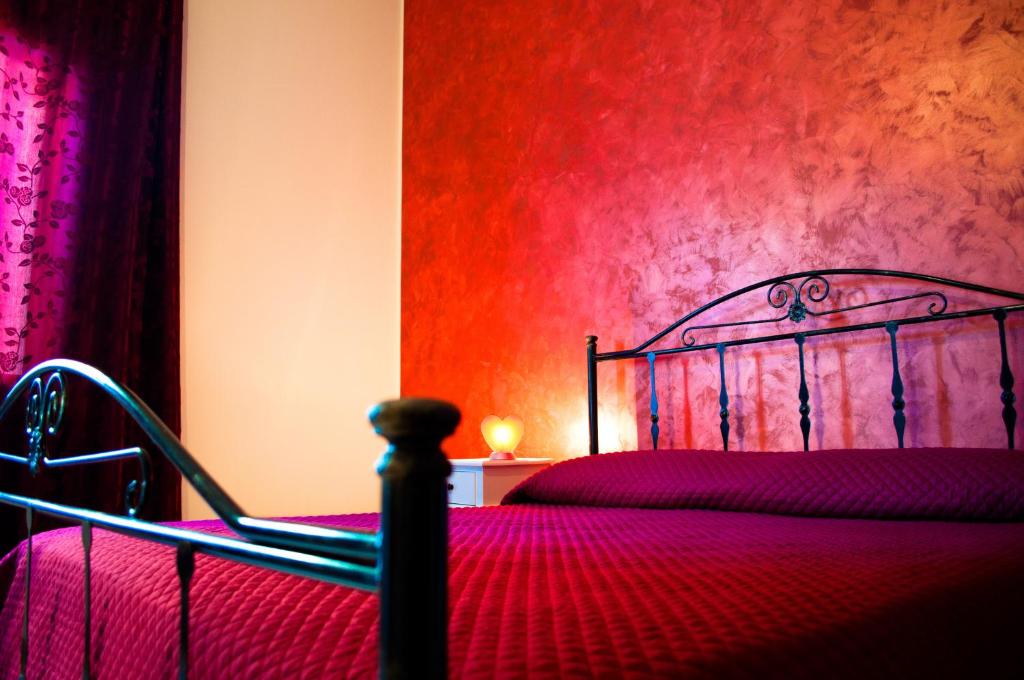 a bedroom with a bed and a red wall at B&B Libertà Marsala in Marsala