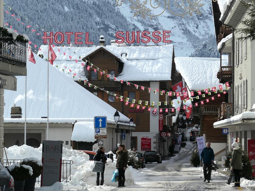 a group of people walking down a snow covered street at Hotel Suisse in Champéry