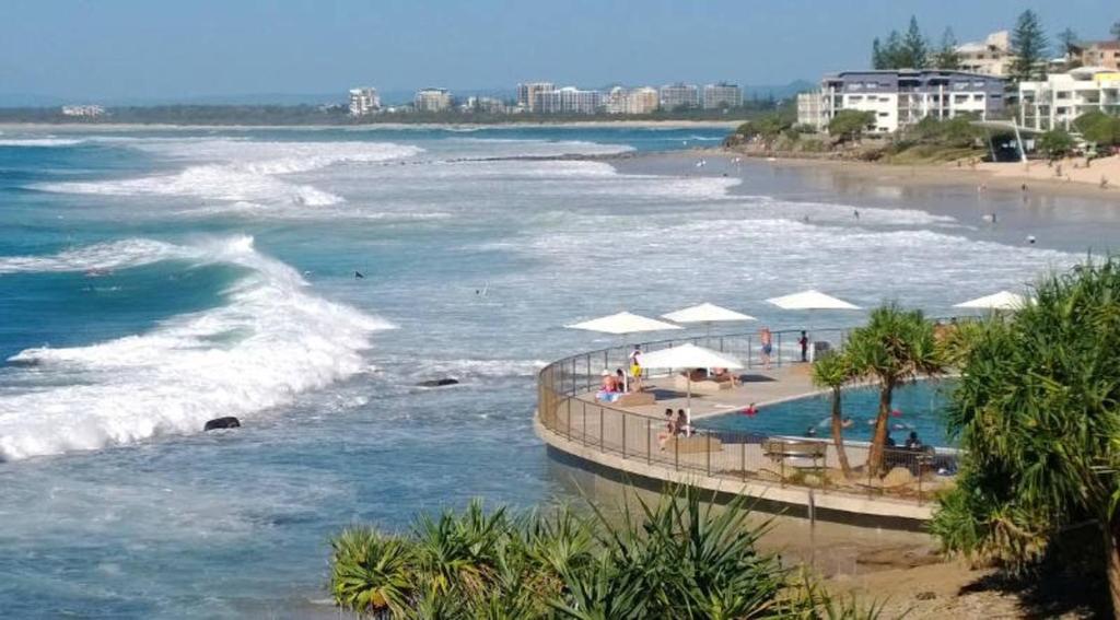 a beach with a swimming pool and the ocean at Family, Romance, Fun on Kings Beach in Caloundra