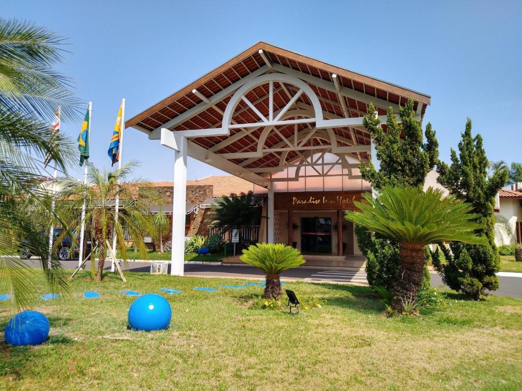 a building with palm trees and blue balls in the grass at Paradise Inn Hotel in Catanduva