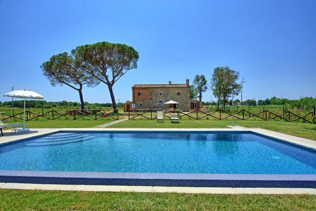 a swimming pool in a field with a building in the background at Villa dei Vini by PosarelliVillas in Terontola