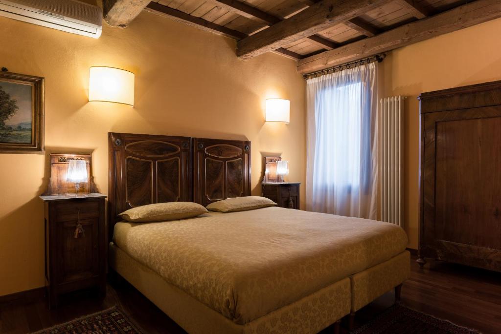 a bedroom with a bed and two lamps and a window at Piazza Nova Guest House in Ferrara