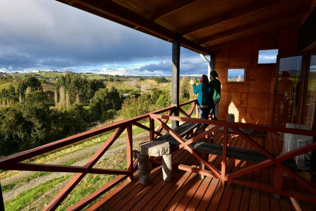 dos personas de pie en una terraza mirando hacia la vista en Hostal Boutique Los Arrayanes, en Castro