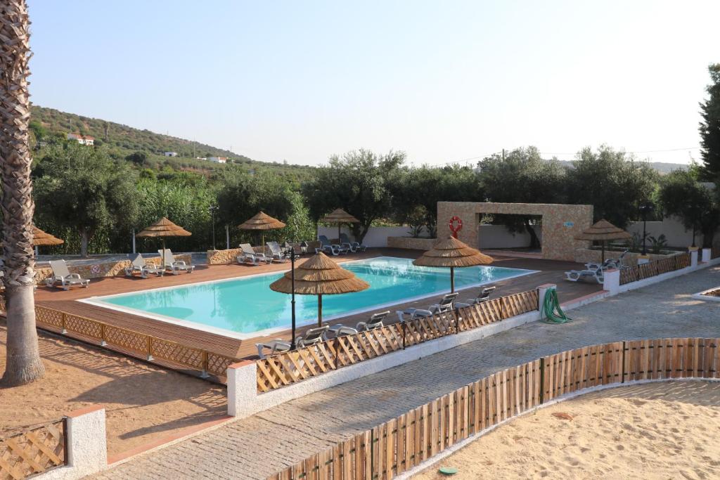 uma grande piscina com guarda-sóis e cadeiras em Casa do Feitor - Monte da Graça em Elvas