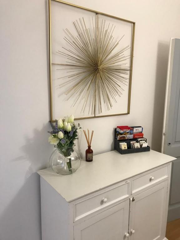 um armário branco com um vaso de flores sobre ele em Romantic and Charming Apartments em Florença