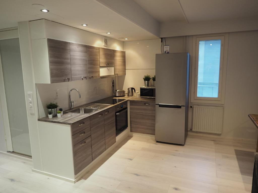uma cozinha com um frigorífico de aço inoxidável e armários de madeira em Apartment Oulu station suite em Oulu