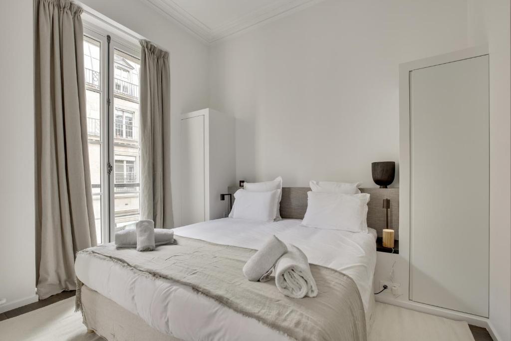 a white bedroom with a large bed with towels on it at Modern Apt 3BDR&#47;3BATH - Louvre Museum&#47;Tuileries in Paris