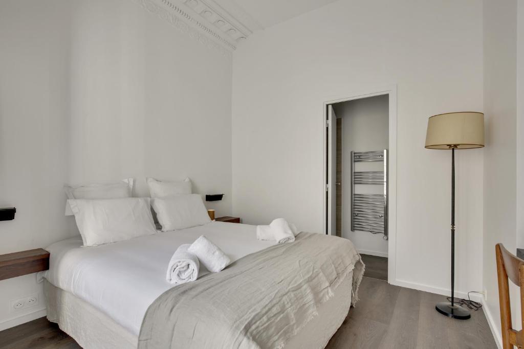 a white bedroom with a large bed with white pillows at Modern Apt 3BDR&#47;3BATH - Louvre Museum&#47;Tuileries in Paris