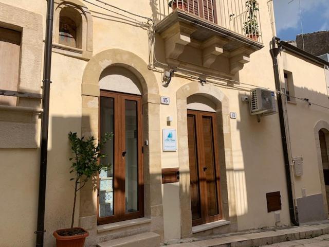 um edifício com arcos e uma varanda numa rua em alex rooms em Ragusa