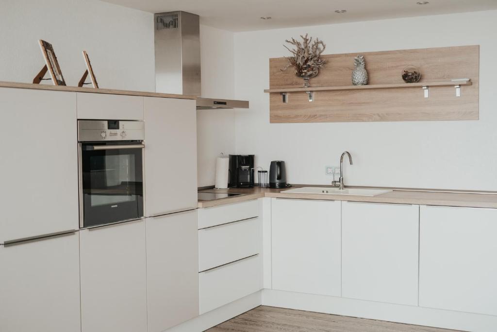 a white kitchen with white cabinets and appliances at Kiba Panorama Suite Oberteuringen 73 Seeblick & Hallenbad in Oberteuringen