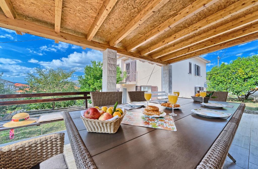 drewniany stół z koszem owoców i kieliszkami do wina w obiekcie Apartmani MARINA w Trogirze