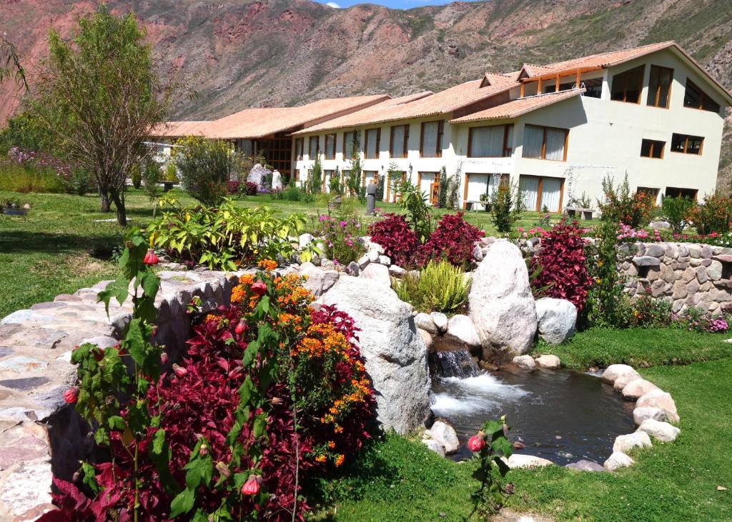 ein Gebäude mit Blumen und einem Teich davor in der Unterkunft Taypikala Deluxe Valle Sagrado in Urubamba