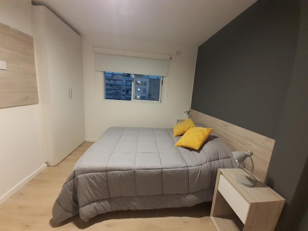 um quarto com uma cama com almofadas amarelas e uma janela em Departamento centrico Alvear em Paraná