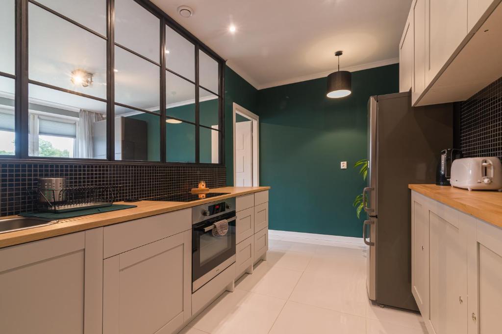 a kitchen with white cabinets and green walls at Main Street Studio in Gdańsk